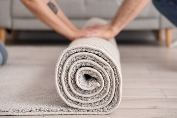 Young couple rolling out carpet in room on moving day, closeup