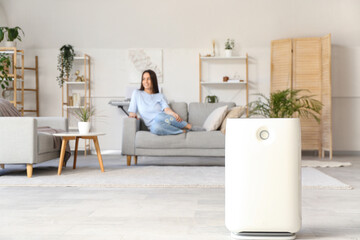 Modern humidifier and young woman resting in living room