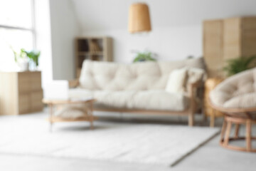 View of blurred living room with sofa, plants and laptop on table