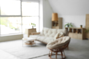 View of blurred living room with sofa, armchair and laptop on table