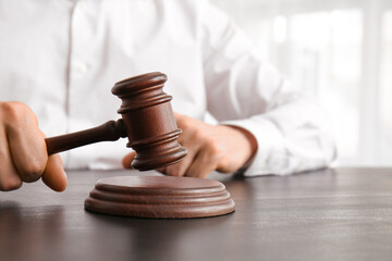 Male lawyer with judge gavel sitting by table in office, closeup