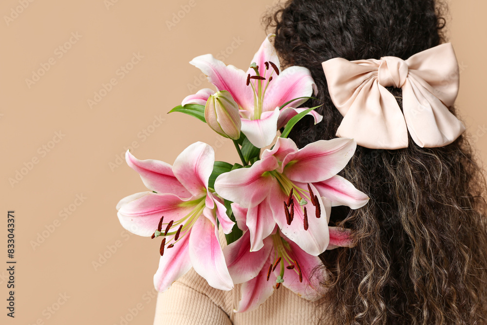 Poster beautiful young african-american woman with pink lily flowers on beige background, back view