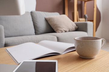 Cup of tea with magazine on table in living room, closeup