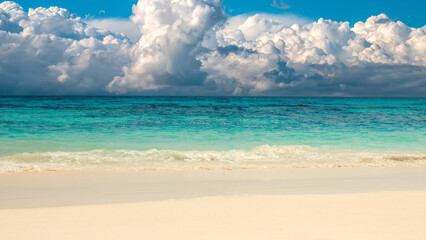 Beautiful sandy beach with white sand and rolling calm wave of turquoise ocean on Sunny day on...