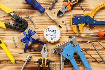 Tools, gift box and greeting card with text HAPPY FATHER'S DAY on wooden background