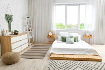 Comfortable bed and chest of drawers in interior of cozy bedroom