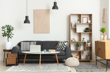 Interior of stylish living room with black sofa, coffee table, chest of drawers and shelving unit