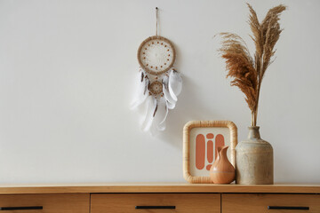 Vase with pampas grass and frame on commode in light room