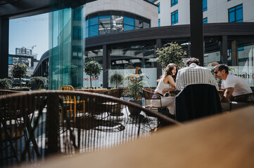 Three business professionals engage in a discussion at an outdoor cafe in the city, illustrating...