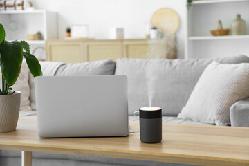 Air humidifier with laptop on table in living room, closeup