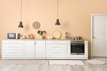 Interior of beautiful kitchen with white counters, microwave and lamps