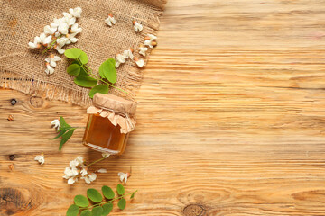 Jar of sweet honey with acacia flowers on wooden background