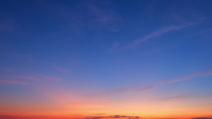 A beautiful sunrise with a clear sky transitioning from deep blue at the top to vibrant orange at...