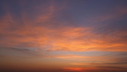 A breathtaking sunrise with the sky filled with warm hues of orange and pink blending seamlessly into darker shades of purple and blue. The clouds add texture to the sky. Sunrise sky background.
