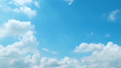 Obraz premium A beautiful blue sky filled with large, fluffy white clouds. The clouds are scattered across the sky, creating a sense of depth and dimension, enhancing the overall serene and calming atmosphere. 