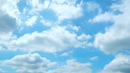 A bright blue sky dotted with fluffy white clouds. The clouds vary in size and shape, creating a dynamic and lively scene. The vibrant blue background adds a sense of freshness and tranquility.
