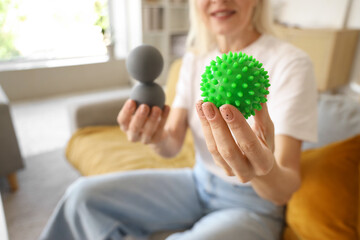 Mature woman with massage balls sitting on sofa at home, closeup