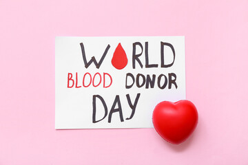 Paper sheet with text WORLD BLOOD DONOR DAY  and heart on pink background. World Blood Donor Day