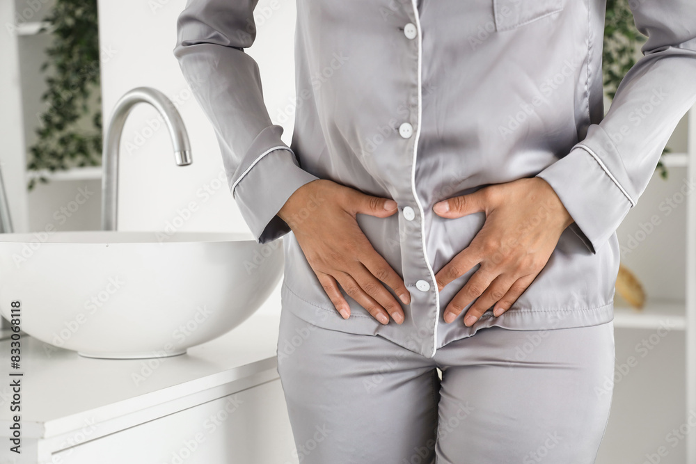 Wall mural young woman suffering from menstrual cramps in bathroom, closeup