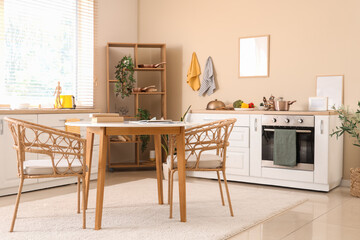 Interior of modern kitchen with dining table, white counters and blank frames hanging on beige wall