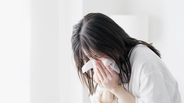 部屋で鼻をかむ女性
