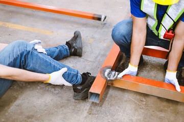 Accident: A male factory worker was injured when a steel frame fell on his leg. and colleague helped lift the steel frame from the injury's leg.