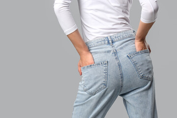 Beautiful young woman in stylish jeans on grey background, closeup