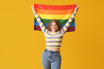Happy young woman with LGBT flag on yellow background