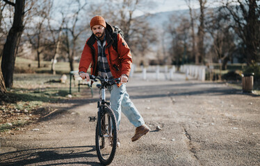 Fototapeta premium An active man in casual attire enjoys a leisurely bike ride in a serene park setting with autumn vibes.