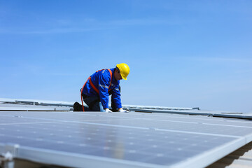 Caucasian engineer is installing solar panels on the roof of industrial factory.