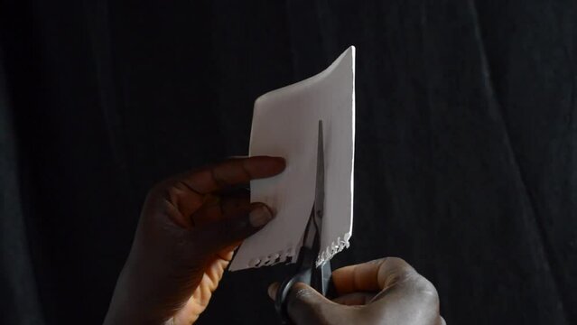 hands with a paire of scissors cutting paper.