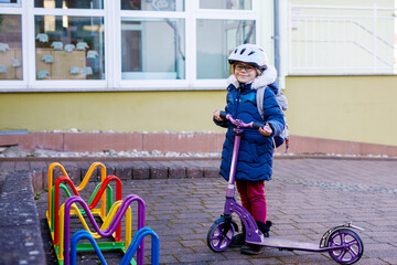 Little girl parking her push scooter by kindergarden or nursery, school parking slot. Happy child...