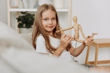 Little girl sitting on a cozy couch, lovingly holding and smiling at her cherished wooden doll