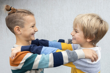 Two brothers or friends 7 years old, facing each other, hugging each other, having fun. the joy of communication, pampering, a joyful meeting of classmates after the holidays. childhood