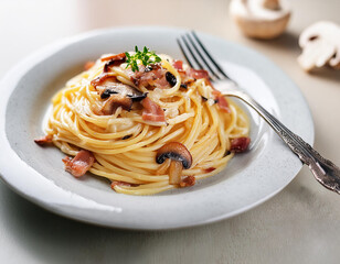 A plate of spaghetti with Cabonara cream and mushroom with fork on table