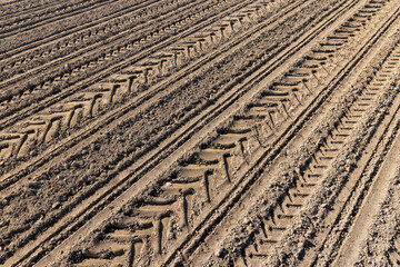 a plowed agricultural field with traces of a tractor