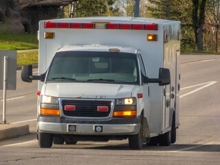 A front view of a plain white ambulance moving down the road.