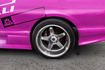 Lowered drift car. Stance Wheel with a beautiful wide rim, low tire profile. Pink car, silver rim