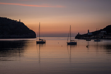 Port de Sóller harbor entrance in the warm glow of the setting sun with anchored sailing boats...