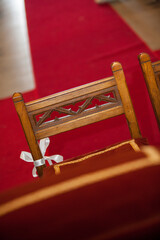 A stunning wooden church pew with intricate design, ribbon on a red carpet, creates a beautiful and...