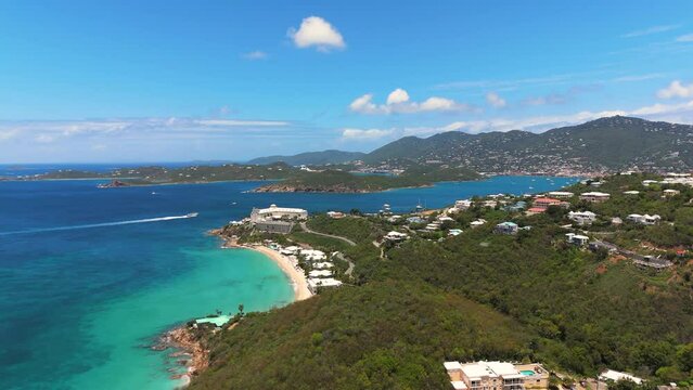 wide rising capture of st. thomas in the virgin islands during a bright summer day from a drone showing many boats, houses, and hotels on the island