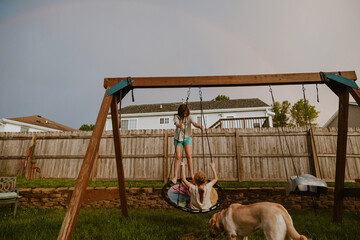 Kids and Dog Playing outside on swing set with Rainbow