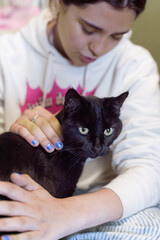 Black Cat Held by a Multiracial Female with Blue Nail Polish
