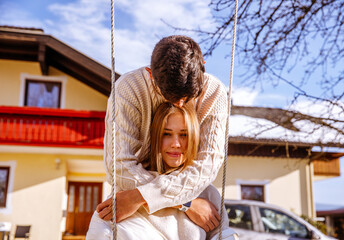 Couple enjoying time together on a swing in front of their house