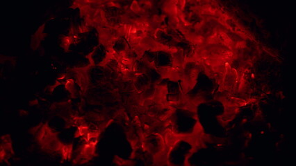 Campfire from branches burns at night. Logs are burning and sparks are flying. Macro view.