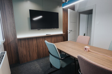 Elegantly designed office space featuring a wooden conference table, comfortable chairs, and a large screen for presentations.
