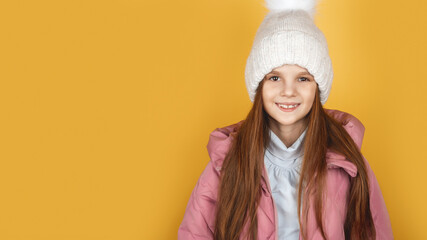 Little girl in padded warm coat. Seasonal fashion. Winter holidays. Fashion child winter clothes. Kid wear hat and jacket yellow background.