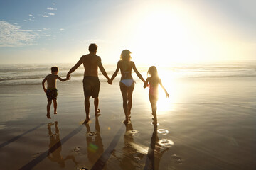 Fototapeta premium Family, beach and holding hands in sunset for holiday, vacation and summer together. Back of parents, people and children in swimwear by ocean and sunshine for support, love and security or travel