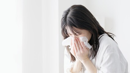 部屋で鼻をかむ女性