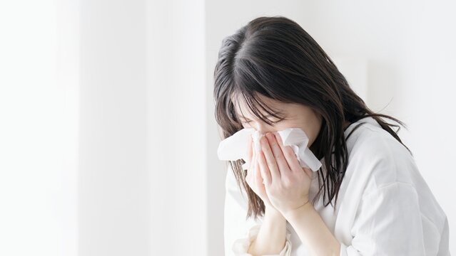 部屋で鼻をかむ女性